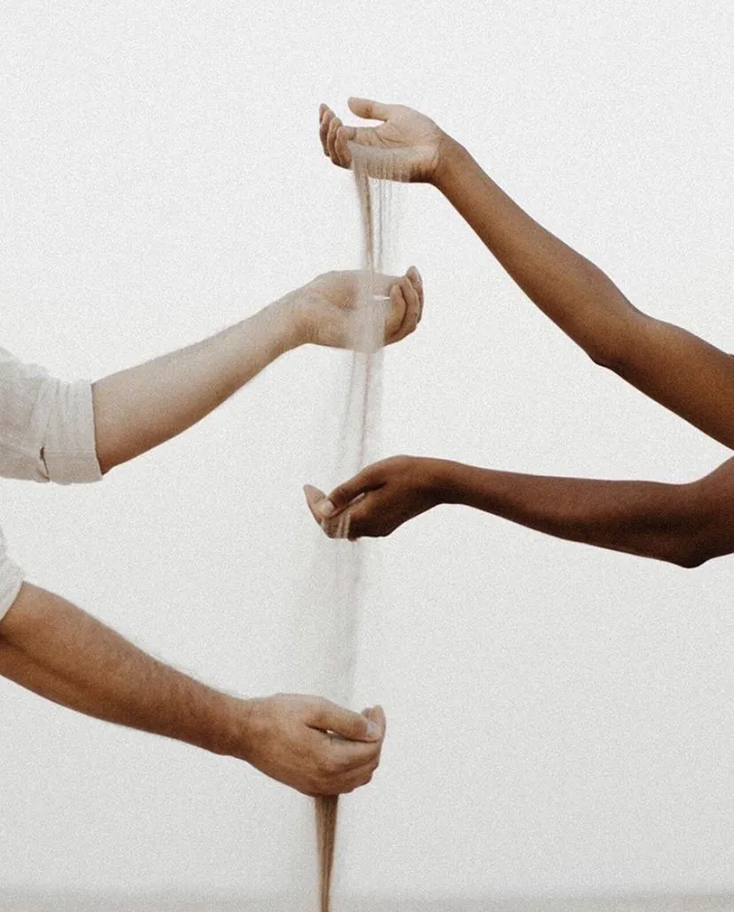 Mãos que compartilham areia — construção conjunta